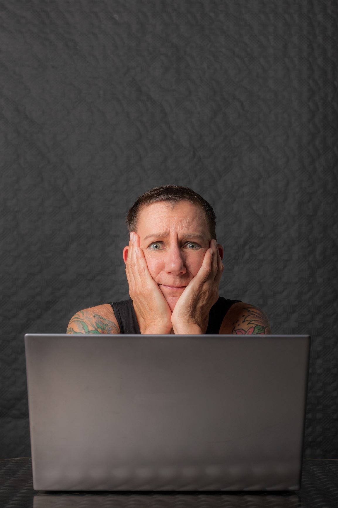 Sabine Scholze sitzt mit besorgtem Gesichtsausdruck vor einem Laptop und hat den Kopf auf die Hände gestützt. Sie denkt über Ziele und Druck nach.