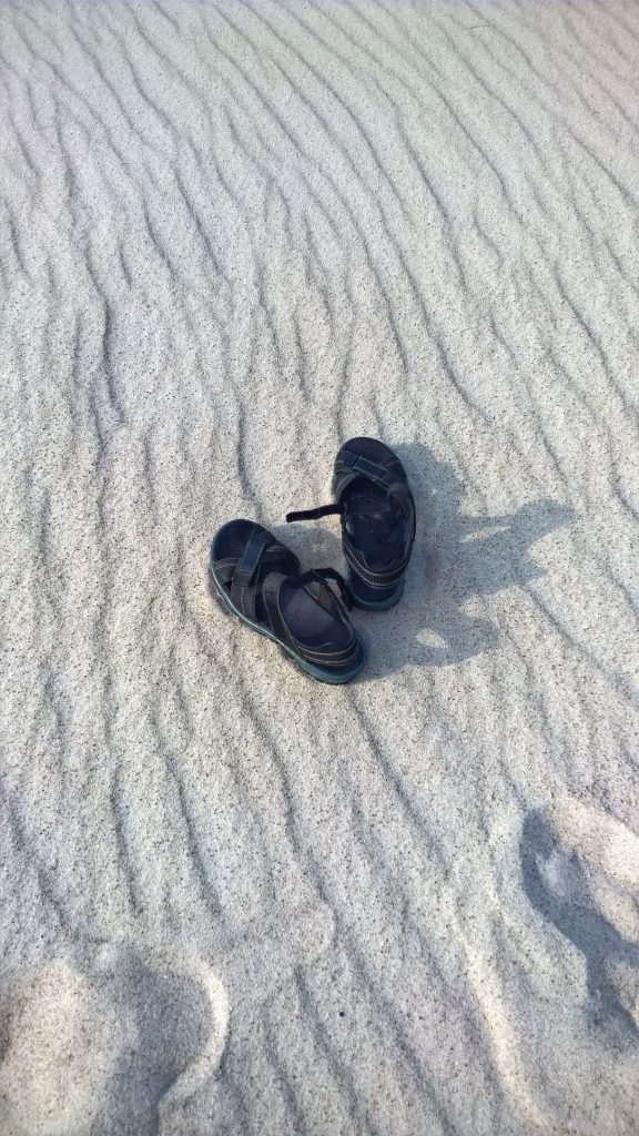 Ein paar Sandalen im Sand symbolisieren das Gefühl, allein dazustehen. Darum die Bitte: Dreh Dich nicht weg!