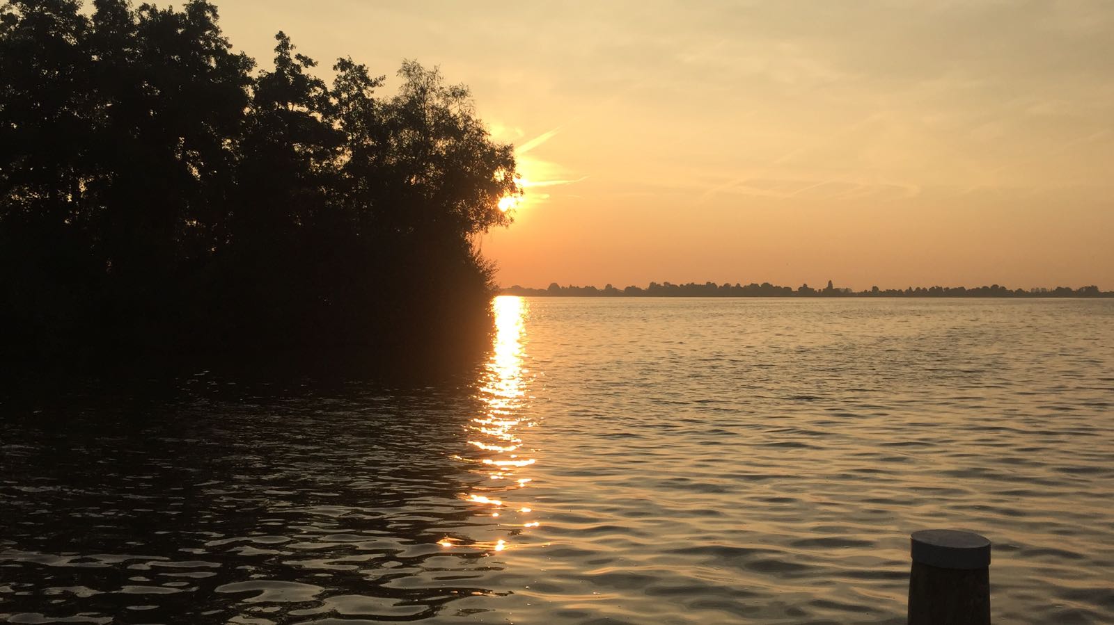 Ein Sonnenaufgang an einem See. Die Sonne spiegelt sich im Wasser.