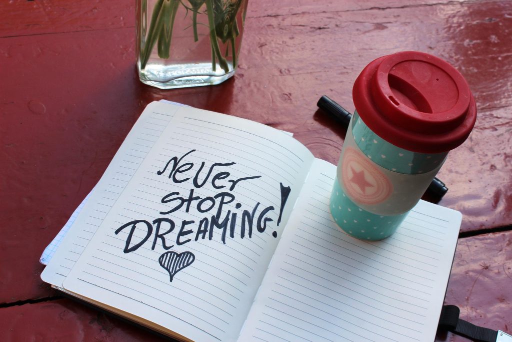 Ein weiteres Zitat: "Never stop dreaming" in einem Heft mit Kaffeebecher daneben.