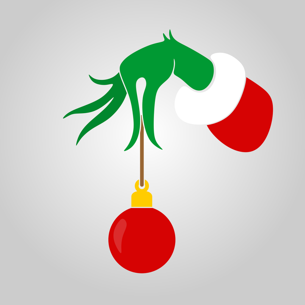 Die Hand des Grinch hält eine rote Weihnachtskugel mit spitzen Fingern.